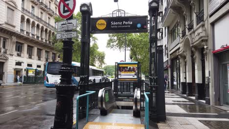 Entrada-A-La-Estación-De-Metro-Saenz-Peña-En-El-Centro-Bajo-La-Lluvia-Con-Autobuses-En-Las-Calles-De-La-Ciudad