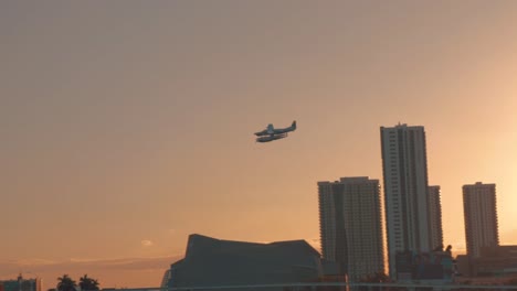 Hidroavión-Volando-Bajo-Sobre-Un-Puente-En-Miami-Durante-La-Puesta-De-Sol,-Panorámica-Hacia-La-Izquierda