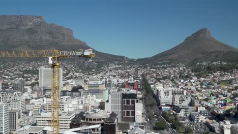 Ein-Turmdrehkran-Arbeitet-Auf-Einer-Städtischen-Hochhausbaustelle-Mit-Tafelberg-Und-Löwenkopf-Als-Hintergrund-Im-Geschäftsviertel-Von-Kapstadt