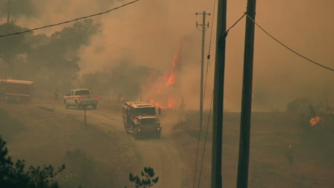 Firetrucks-and-vehicles-at-a-raging-forest-fire,-haze-in-the-highlands-of-California,-USA