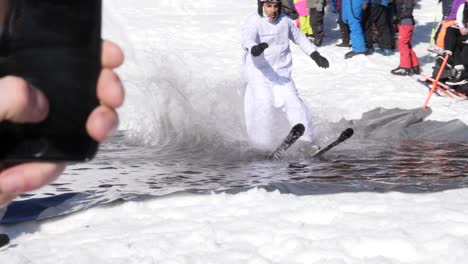 Ein-Mann-Fährt-In-Zeitlupe-Einen-Schneehügel-Hinunter-Und-über-Ein-Eiskaltes-Wasserbecken