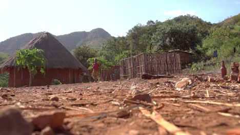 Cute-young-African-boy-child-in-traditional-rural-village-runs-past-camera