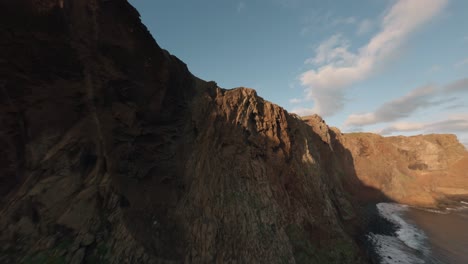 FPV-Drohne-Kreuzt-Bei-Sonnenaufgang-Am-Rande-Der-Bergkette-Am-Strand-Von-Ponta-Do-Rosto