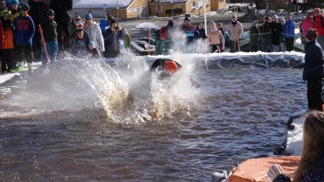 At-a-community-contest,-a-man-snowboards-down-a-hill-then-wipes-out-in-the-pool-of-water-after-trying-a-stunt