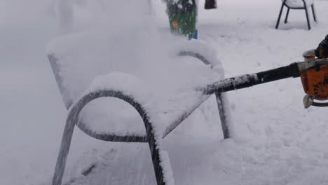 Trabajador-Quitando-Nieve-Helada-De-Un-Banco-Público-En-El-Parque-Con-Un-Soplador-De-Hojas