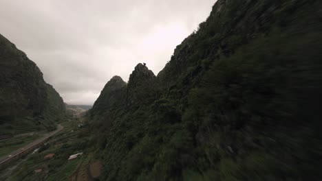 Dron-Fpv-Volando-En-Las-Montañas-Nubladas-Sobre-Una-Cresta-Montañosa-Cerca-De-Los-Exuberantes-árboles-Y-Rocas-Verdes