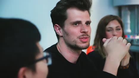 Male-handsome-student-smiling-and-talking-during-brainstorm-session-in-class