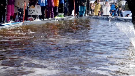 Man-skis-down-a-hill-but-one-ski-comes-off-as-he-is-crossing-the-pool-of-water-at-the-end-of-the-run---slow-motion