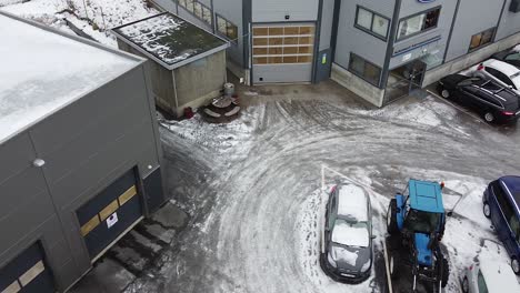 Cars-parked-in-front-of-an-industrial-business-center-on-a-cold-winter-day-with-light-snow---aerial-view