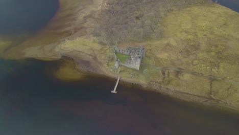 Toma-Aérea-De-Arriba-Hacia-Abajo-Del-Famoso-Castillo-De-Kilchurn-Y-El-Lago-Loch-Awe-Durante-El-Día-De-Niebla,-Escocia