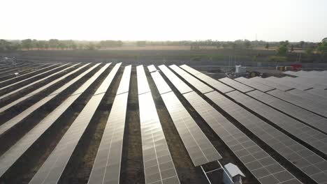 Vista-Aérea-Por-Drones-De-La-Luz-Del-Sol-Cayendo-Sobre-Paneles-Solares-Y-El-Amanecer-Moviéndose-Hacia-El-Sitio