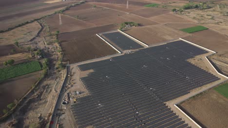 Aerial-drone-view-showing-many-dolar-power-plant-and-big-power-station-in-the-house-and-big-fields-around