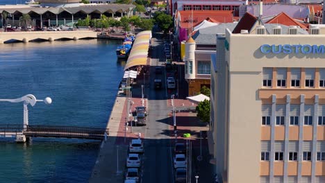 Drohne-Steigt-Herab,-Während-Autos-Entlang-Der-Handelskade-Punda-Im-Bezirk-Willemstad-Curacao-Fahren