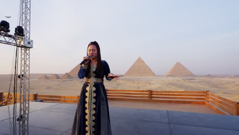 A-singer-performs-on-a-stage-overlooking-pyramids,-Giza-in-Egypt-close-up-shot