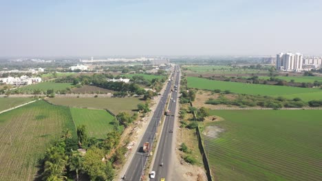 Luftdrohnenansicht-Drohne-Vor-Großen-Feldern-Und-Vielen-Fahrzeugen,-Die-Sich-Auf-Der-Straße-Bewegen