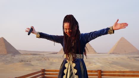 Un-Cantante-Actúa-En-Un-Escenario-Frente-A-La-Audiencia-Con-Vista-A-Las-Pirámides,-Giza-En-Egipto-Toma-De-Arco