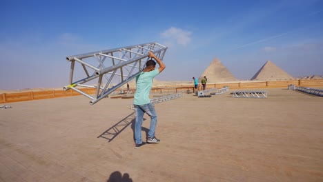 La-Gente-Prepara-El-Escenario-Para-Una-Fiesta-En-El-Desierto-Junto-A-Las-Pirámides,-Giza-En-Egipto,-Toma-De-Establecimiento,-Toma-De-Seguimiento