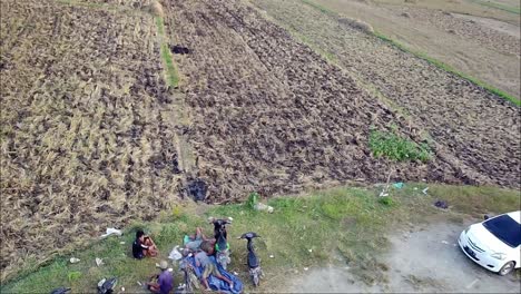 La-Gente-Observa-Un-Dron-Descender-Frente-A-Los-Campos-De-Arroz-Después-De-La-Cosecha-Por-La-Mañana-En-Blora,-Indonesia.