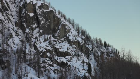 Smiling-young-male-hiker-carries-camera-gimbal-as-he-walks-by-snowy-peak