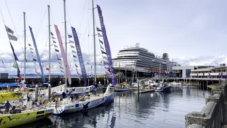 Cruise-Ship-docked-with-sail-boat-and-colorful-flags-waving-in-the-wind