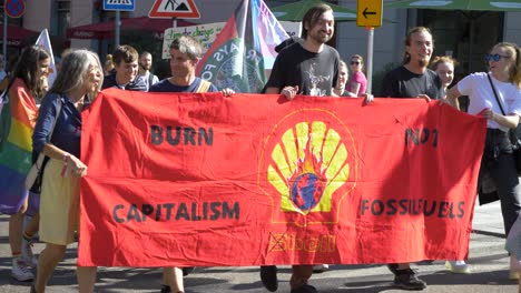 Fridays-For-Future-FFF-Protest-Mit-Jungen-Und-älteren-Aktivisten,-Die-Gemeinsam-Marschieren-Und-Dabei-Ein-Schild-Mit-Der-Aufschrift-„Verbrenne-Kapitalismus-Statt-Fossile-Brennstoffe“-In-Stuttgart,-Deutschland,-Hochhalten