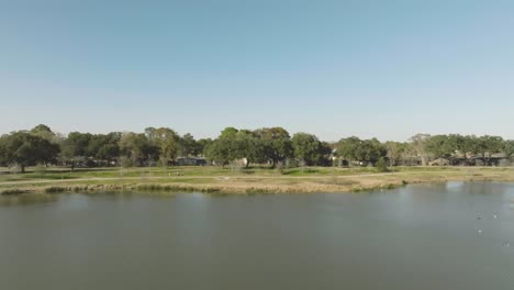 An-aerial-view-of-two-cyclists-riding-their-bicycles-on-a-bike-path-around-the-pond-at-Exploration-Green-in-Clear-Lake,-Houston,-Texas