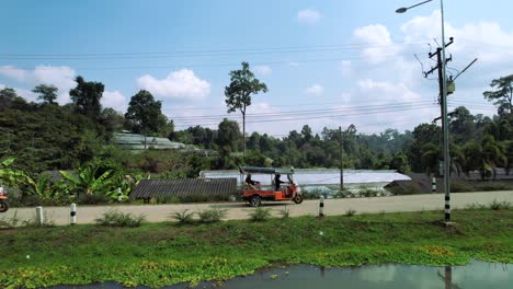 Tourists-Travel-on-Tour-Riding-Tuk-Tuk-Auto-Rickshaw-in-Chiang-Mai-Countryside,-Thailand---Aerial-tracking