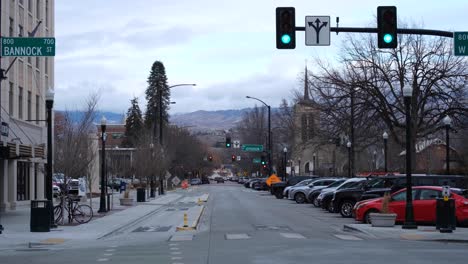 Scenic-street-view-lined-with-parked-vehicles-and-traffic-and-mountain-landscape-in-the-distance,-state-of-Idaho,-USA