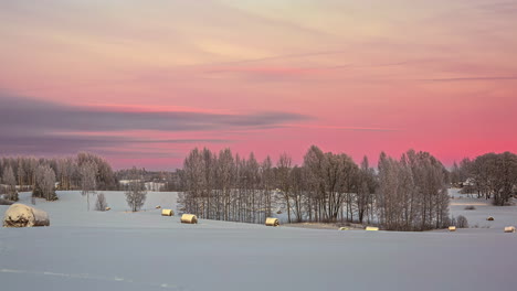 During-the-golden-hour,-the-sky-changes-from-light-yellow-to-red-over-a-winter-landscape