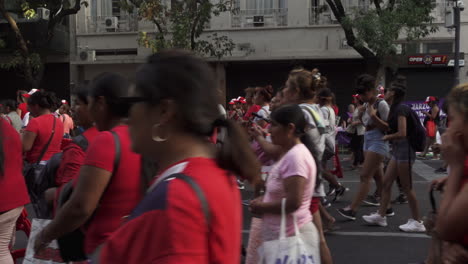 protestors-dressed-in-red-march-to-claim-their-rights-on-streets-of-buenos-aires,-hold-signs