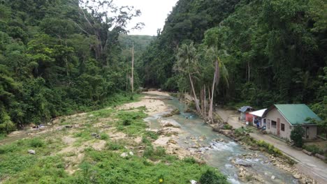 Filipino-villagers-going-about-their-daily-routine,-bathing-and-cleaning-in-creek-water-by-their-home-secluded-in-tropical-jungle