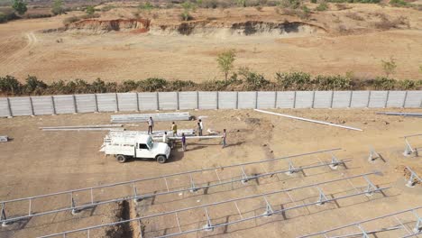 Aerial-drone-view-Men-unloading-steel-rods-from-trucks-and-many-solar-panels