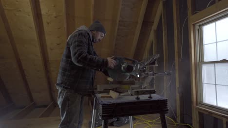 Hombre-Cortando-Madera-Con-Sierra-Ingletadora-En-Un-Taller,-Aserrín-Volando,-Artesanía-Enfocada