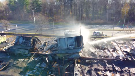 Aerial-View-Of-Roof-Fire-Collapse-Of-Warehouse-With-Fire-Department-Using-Ladder-To-Extinguish-Flames