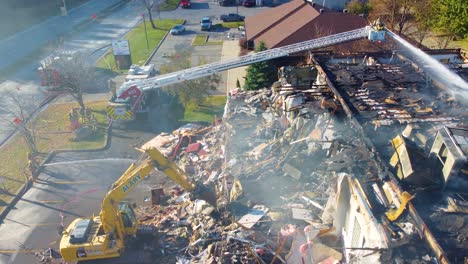 Aerial-View-Of-Roof-Fire-Collapse-Of-Warehouse-With-Fire-Department-Using-Ladder-To-Extinguish-Flames