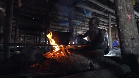 Indonesian-cooking-in-open-fire-pot-inside-traditional-house-hut-for-single-men