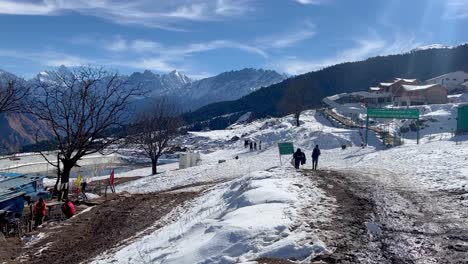 In-Der-POV-Aufnahme-Laufen-Viele-Menschen-Durch-Den-Schnee-Und-Man-Sieht-Viele-Häuser-Und-Es-Gibt-Auch-Viele-Große-Berge