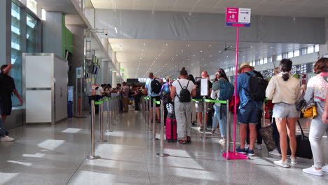 People-waiting-at-the-gate-in-line-to-board-an-airplane-in-Malaga-international-airport,-Starbucks-in-the-background,-holiday-vacation-time,-4K-shot