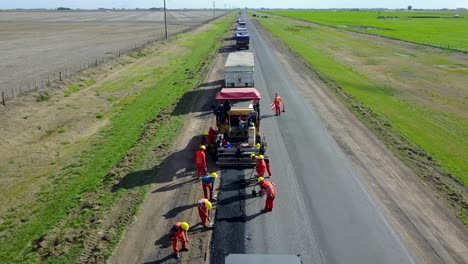 Vista-Aérea-De-Trabajadores-Con-Ropa-De-Alta-Visibilidad-Pavimentando-Caminos-En-Zona-Rural-Cerca-De-Buenos-Aires