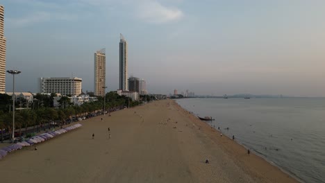 Aerial-view-of-sunset-on-wide-sandy-beach-and-people-sitting-on-the-sand