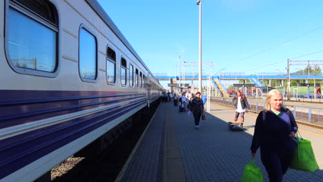 Gente-Caminando-Con-Maletas-Junto-Al-Tren-Ukrzaliznycia-De-Los-Ferrocarriles-Ucranianos-En-La-Estación-De-Tren-De-Chelm-En-Polonia,-Gente-Viajando,-Clima-Soleado,-Tomas-De-4k