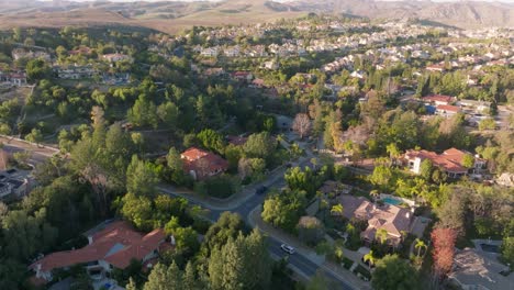 Flug-über-Das-Gehobene-Viertel-Von-Calabasas,-Kalifornien-Bei-Sonnenuntergang-Mit-Bergen-Am-Horizont-Und-Darunter-Fahrendem-Auto