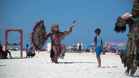 Cámara-Lenta-De-Un-Hombre-Latino-Vestido-Como-Un-Guerrero-águila-Maya-Bailando-Y-Actuando-Para-El-Turista-En-Una-Playa-En-Cancún-México