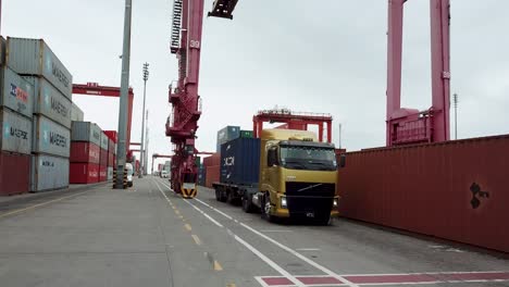 Truck-passing-through-a-busy-container-terminal-during-daytime,-with-cranes-and-stacked-shipping-containers-Port-of-buenos-aires