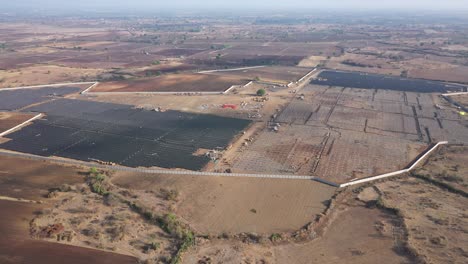 Vista-Aérea-De-Drones-Cámara-De-Drones-Moviéndose-Hacia-Atrás-Donde-Se-Está-Construyendo-Una-Gran-Cantidad-De-Plantas-De-Energía-Solar-En-Una-Gran-Granja