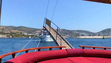 Holzheck-Auf-Einem-Großen-Segelboot-In-Bodrum,-Türkei,-Mit-Vorbeifahrenden-Yachten,-Lustiger-Sommerurlaub,-Die-Rückseite-Eines-Fahrenden-Bootes,-Luxusurlaubsziel,-Sonniger-Seetag-Mit-Blauem-Himmel,-4K-Aufnahme