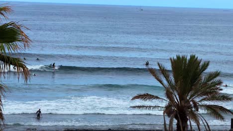 Beach-waves,-volcanic-island-with-black-sand,-palm-trees-relaxing-calming-sea