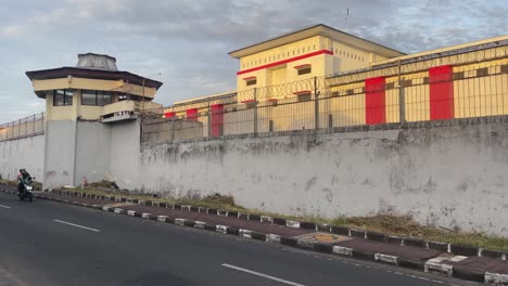 Steady-shot-with-short-panning-of-a-Jail-as-cars,-and-scooters-passing-by-on-the-street