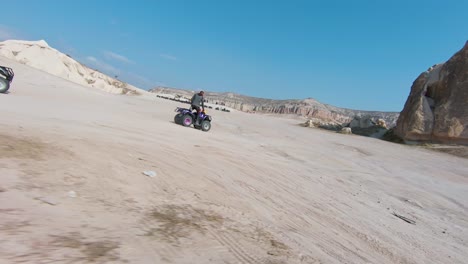 ATV-Tour-In-Cappadocia---Tourists-On-Quad-Bikes-Driving-On-Arid-Terrain-In-Cappadocia,-Turkey-With-View-Of-Fairy-Chimneys