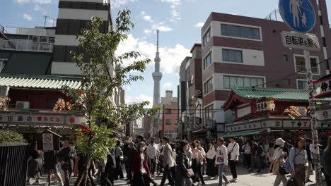 Busy-Crowds-Crossing-Nakamise-dori-Street-With-View-Of-Tokyo-Sky-Tree-In-Background-On-Clear-Sunny-Day